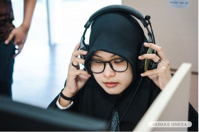 SEMANGAT-PENUH HARAP: Abidah Ardelia peserta tunanetra asal Sidoarjo tampak antusias mengikuti UTBK di Unesa. Ia mengenakan alat ‘pembaca soal’ teks menjadi audio.